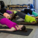 Adults lying on yoga mats performing Pilates stretches