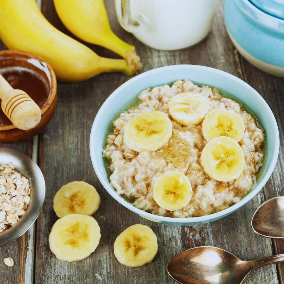 A blue bowl of cooked oats with slices of banana and honey